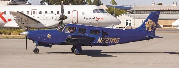 A bright blue Piper PA-32R-300 Lance with a tail number of N22WG parked in front of a larger airplane.
runway.