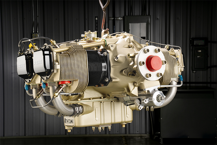A Continental IO-370 aircraft engine painted in gold and black, suspended by a hook in a workshop setting.