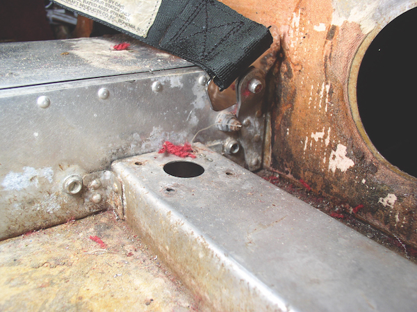 Close-up of corrosion and red fiber remnants after carpet was removed in a Piper aircraft.