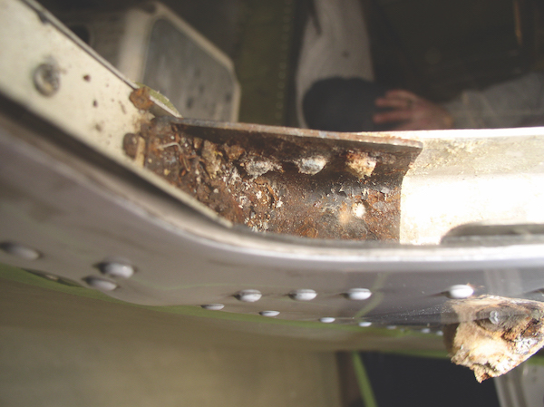 Close-up of rust on a steel reinforcement bracket in a Piper aircraft.
