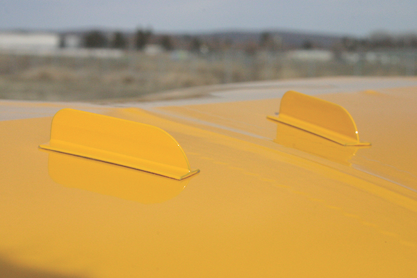 Close-up of two small, yellow, curved vortex generator fins mounted securely to an aircraft wing.