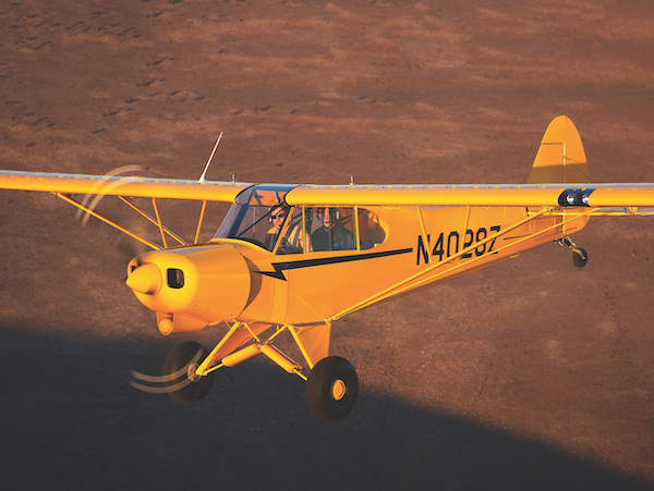 The Best Bang-For-Your-Buck Piper Modification: Vortex Generators A yellow Piper Super Cub aircraft with tail number N40287 flying low over flat ground during a late afternoon flight.